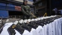 Polisi berjaga di dekat senjata sitaan yang akan dimusnahkan di pabrik metalurgi di Nobsa, Kolombia, Kamis (5/12/2024).
