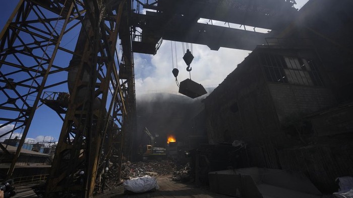 A police stands guard over seized weapons to be destroyed at a metallurgic plant in Nobsa, Colombia, Thursday, Dec. 5, 2024. (AP Photo/Fernando Vergara)