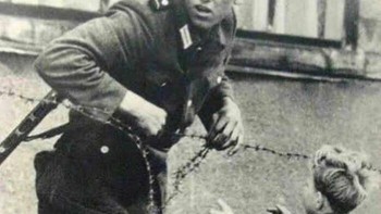 Tentara Jerman Timur membantu seorang anak laki-laki pada 1961, hari Tembok Berlin didirikan. Bocah itu terpisah karena keadaan chaos di mana orang-orang berusaha kabur bersama keluarga mereka. Foto: historians via Bored Panda