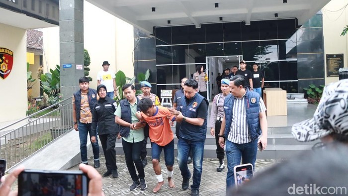 Yusak dikeler polisi untuk menuju ke ruang konferensi pers di Polres Kediri.