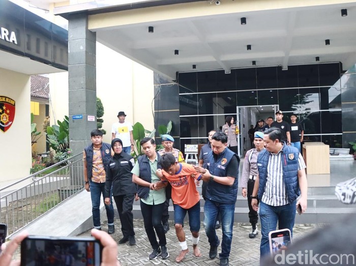 Yusak dikeler polisi untuk menuju ke ruang konferensi pers di Polres Kediri.