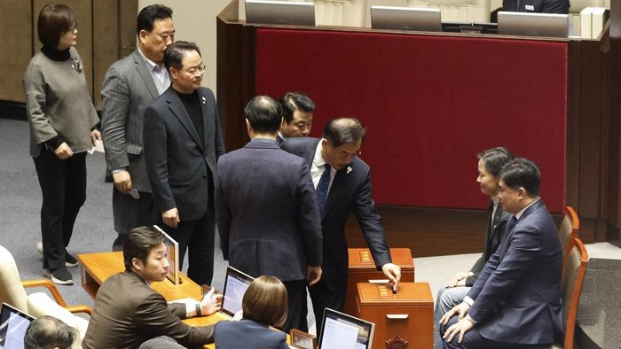 Lawmakers queue to cast their votes on the impeachment motion against President Yoon Suk Yeol at the National Assembly in Seoul on December 7, 2024. South Korean lawmakers started voting on December 7 on a motion to impeach President Yoon Suk Yeol over his short-lived declaration of martial law, even after most ruling party MPs boycotted, a live TV feed showed. (Photo by JEON HEON-KYUN / POOL / AFP)