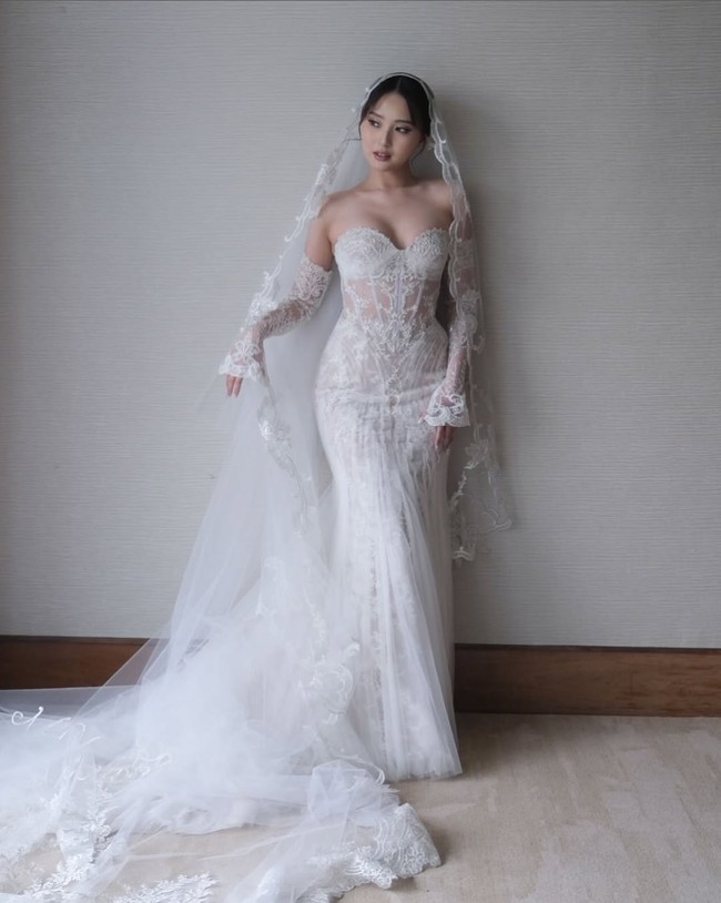 Veil panjang dengan ujung renda menambah kesan dramatis dan romantis, sementara aksen renda pada lengan menambah kesan anggun sekaligus berani. Gaun ini cocok untuk mempelai yang ingin tampil glamor namun tetap menonjolkan sentuhan personal di hari istimewanya. Foto: Instagram