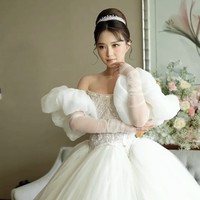 Bagian torso dihiasi detail kristal  an sulaman rumit yang menonjolkan nuansa elegan dan mewah. Lengan puff off-shoulder dengan material transparan menciptakan kesan romantis dan lembut, dilengkapi dengan sarung tangan sheer panjang yang memberi sentuhan vintage. Foto: Instagram