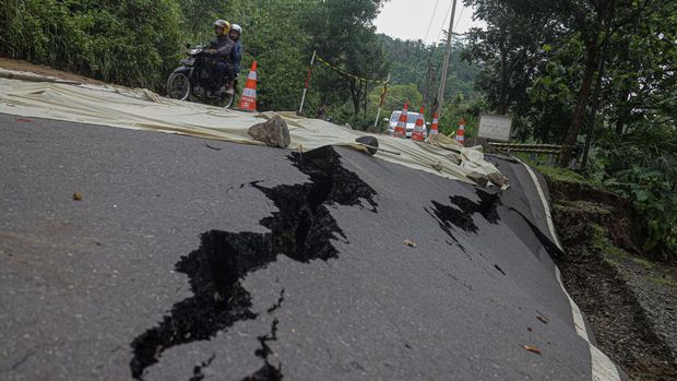 Warga melihat jalan yang terbelah akibat longsor di Pelabuhan Ratu, Kabupaten Sukabumi, Jawa Barat, Sabtu (7/12/2024). Pergerakan tanah disebabkan oleh tingginya intesitas hujan di kawasan tersebut, mengakibatkan akses jalan menuju tempat wisata tidak bisa dilintasi oleh kendaraan roda empat. ANTARA FOTO/Yulius Satria Wijaya/aww.