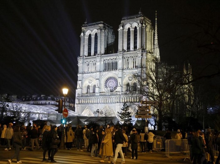 Crowds gather in front of Notre-Dame de Paris cathedral, on the eve of its official reopening after more than five-years of reconstruction work following the April 2019 fire, in Paris on December 6, 2024. Notre-Dame Cathedral is set to re-open early December 2024, with a weekend of ceremonies on December 7 and 8, 2024, five years after the 2019 fire which ravaged the world heritage landmark and toppled its spire. Some 250 companies and hundreds of experts were mobilised for the five-year restoration costing hundreds of millions of euros. (Photo by Ludovic MARIN / AFP)