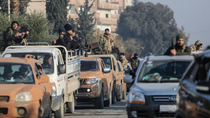 Anti-government fighters drive along a street in Hama after they captured the central Syrian city, on December 6, 2024. Rebel forces pressing a lightning offensive in Syria aim to overthrow President Bashar al-Assads rule, their Islamist leader said in an interview published on December 6. In little over a week, the offensive has seen Syrias second city Aleppo and strategically located Hama fall from Assads control for the first time since the civil war began in 2011. (Photo by Bakr AL KASSEM / AFP)