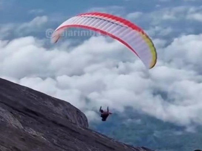 Pendaki, diduga WNA, menggunakan paralayang saat turun dari puncak Gunung Agung, Karangasem, Bali. (Tangkapan layar video viral)