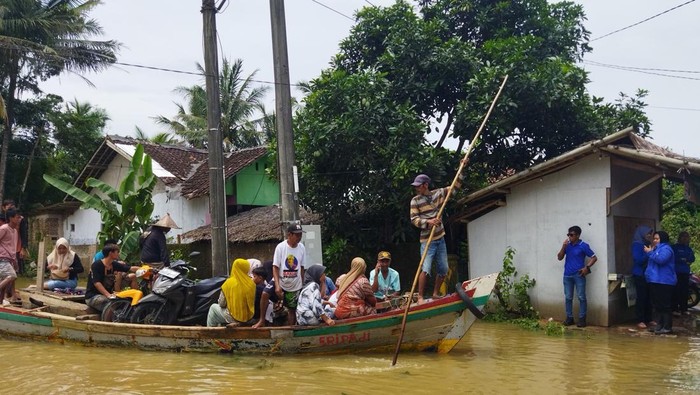 Warga Pandeglang andallkan perahu untuk menyebrang saat akses jalan putus karena banjir.