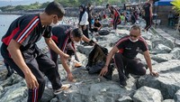 Sejumlah anggota Brimob dan warga yang tergabung dalam Komunitas Warga Peduli Lingkungan menggelar aksi bersih-bersih sampah di Pantai Teluk Palu, Minggu (8/12/2024).