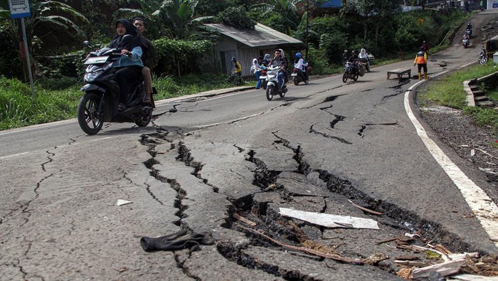 Pengendara motor melewati jalan retak dan amblas di Jalan Raya Baros - Sigaranten, Kabupaten Sukabumi, Jawa Barat, Minggu (8/12/2024). Pergerakan tanah akibat hujan terus menerus tersebut menyebabkan jalan retak dan amblas sehingga berpotensi menyebabkan kecelakaan. ANTARA FOTO/Yulius Satria Wijaya/rwa.