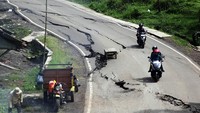 Pengendara motor melewati jalan retak dan ambles di Jalan Raya Baros-Sigaranten, Kabupaten Sukabumi, Jawa Barat, Minggu (8/12/2024).