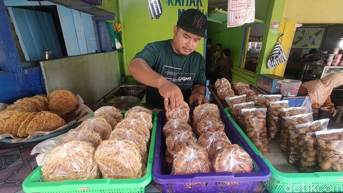 Agus menata peyek yutuk yang baru dimasak di lapaknya sekitar Pantai Widarapayung, Kabupaten Cilacap, Minggu (8/12/2024).