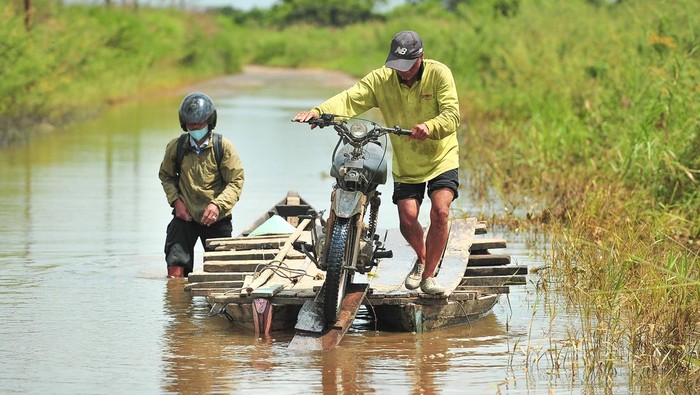 Banjir merendam Jalan Lintas Jambi-Berbak, Jambi. Banjir yang terjadi sejak seminggu terakhir itu dimanfaatkan warga untuk membuka jasa penyeberangan motor.