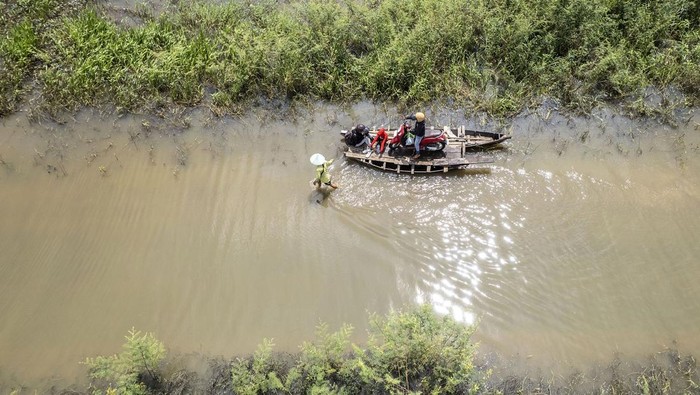 Banjir merendam Jalan Lintas Jambi-Berbak, Jambi. Banjir yang terjadi sejak seminggu terakhir itu dimanfaatkan warga untuk membuka jasa penyeberangan motor.