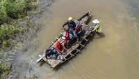 Penyedia jasa menyeberangkan pengendara sepeda motor melewati Jalan Lintas Jambi-Berbak di Gedong Karya, Muaro Jambi, Jambi, yang terendam banjir, Minggu (8/12/2024).