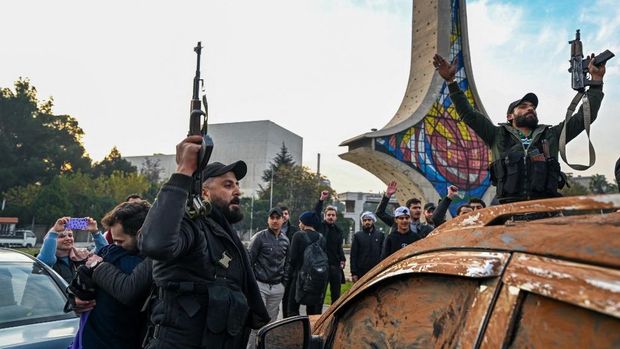 Orang- orang berkumpul di alun-alun utama Damaskus sambil melambaikan tangan dan meneriakkan 'Kebebasan' dari pemerintahan keluarga Assad yang telah berkuasa sekitar 50 tahun. (Photo by LOUAI BESHARA / AFP)