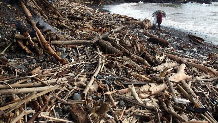 Warga beraktivitas di dekat sampah yang menumpuk di Pantai Loji, Pelabuhan Ratu, Sukabumi, Jawa Barat, Sabtu (7/12/2024). Menurut warga setempat, sampah tersebut  terbawa luapan banjir muara sungai Cimandiri karena cuaca ekstrem yang terjadi pada Rabu (5/12) lalu. ANTARA FOTO/Yulius Satria Wijaya/aww.