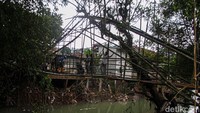 Warga membangun jembatan darurat agar akses desa tetap tersambung. 
