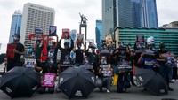 Selain memakai topeng Munir, mereka juga membawa payung berwarna hitam. 