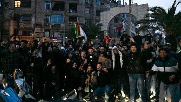 Local residents cheer as the gather on a street in the Damascus suburb of Jaramana on December 8, 2024. Syrian rebels said on December 8 that President Bashar al-Assad had fled the country, calling on citizens abroad to return to a 