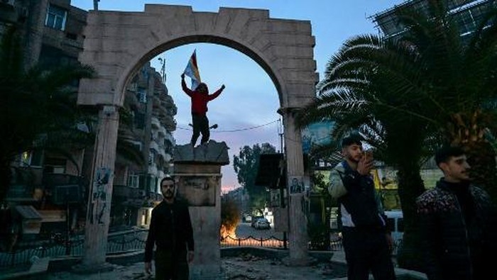 People walk along a street in Damascus on December 8, 2024. Syrian rebels said on December 8 that President Bashar al-Assad had fled the country, calling on citizens abroad to return to a free Syria and saying that Damascus was free of the tyrant. (Photo by LOUAI BESHARA / AFP)