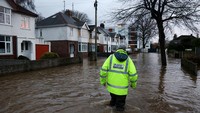 Petugas melintas di jalan yang terendam banjir di Hereford, Inggris, Minggu (8/12/2024) waktu setempat.