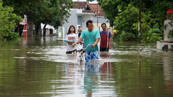 Warga duduk di teras rumah sambil bekerja saat banjir mengenangi Dusun Beluk, Desa Jombok, Kecamatan Kesamben, Kabupaten Jombang, Jawa Timur, Senin (9/12/2024). Dari data BPBD Kabupaten Jombang, banjir akibat luapan sungai Afvour Watudakon itu merendam ratusan rumah dengan ketinggian bervariasi mulai 30 sentimeter hingga 60 sentimeter, selain itu sebanyak 600 jiwa terdampak serta 55 orang mengungsi ke tempat aman. ANTARA FOTO/Syaiful Arif/foc.