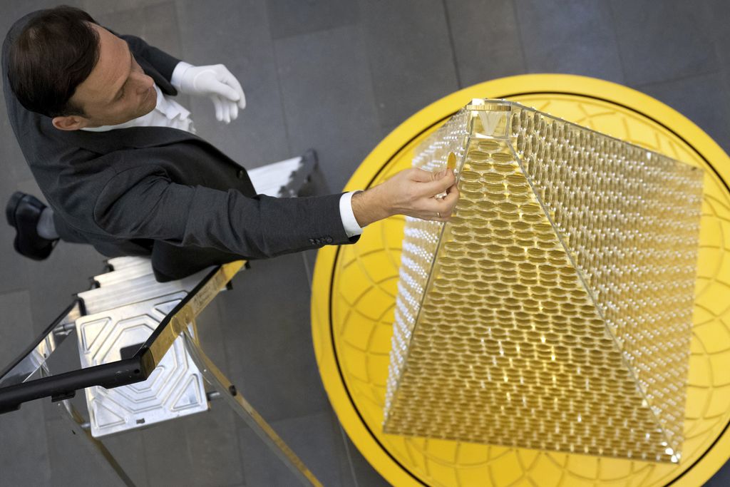 Benjamin Summa, karyawan perusahaan perdagangan emas Munich, meletakkan koin emas di 'Pohon Natal Emas' dengan nilai saat ini sekitar 5,3 juta euro di Munich, Jerman, Selasa, 3 Desember 2024. (Sven Hoppe/dpa/dpa via AP)