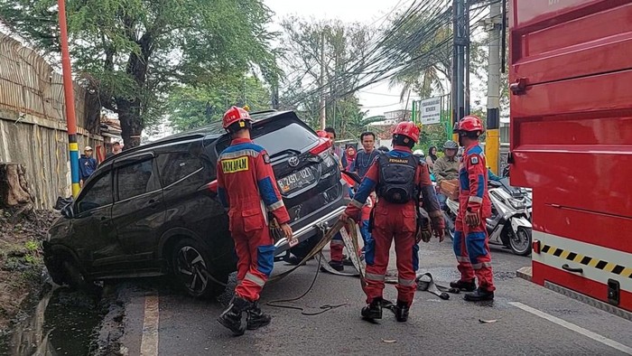 Damkar Jakarta Utara mengevakuasi mobil yang terperosok ke parit di Jalan Tipar Cakung, Cilincing, Jakut.
