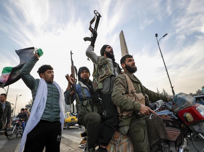 Syrian opposition fighters celebrate after the Syrian government collapsed in Damascus, Syria, Sunday, Dec. 8, 2024. (AP Photo/Omar Sanadiki)