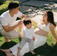 Di pemotretan pertama Nikita bersama suami dan anaknya kompak mengenakan busana berwarna putih. Penampilan ketiganya terlihat santai kala berpose di rerumputan hijau. Foto: Instagram/@nikitawillyofficial94