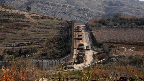 A military vehicle rides next to Israeli soldiers standing guard near the ceasefire line between Syria and the Israeli-occupied Golan Heights, December 9, 2024. REUTERS/Ammar Awad