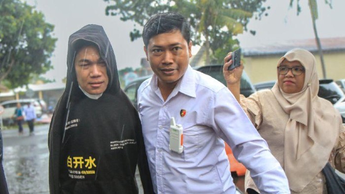 Penyidik kepolisian mendampingi penyandang disabilitas yang menjadi tersangka kasus dugaan pelecehan seksual berinisial IWAS (kiri) berjalan untuk menemui Mensos RI Saifullah Yusuf disela kegiatan pemeriksaan tambahan di Markas Polda NTB, Mataram, Senin (9/12/2024). (ANTARA/Dhimas B.P.)
