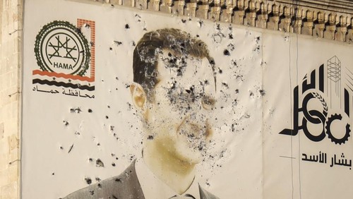 An image of Syrian President Bashar Assad, riddled with bullets, is seen on the facade of the provincial government office in the aftermath of the oppositions takeover of Hama, Syria, Friday, Dec. 6, 2024. (AP Photo/Omar Albam)