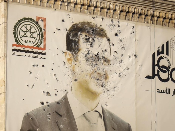 An image of Syrian President Bashar Assad, riddled with bullets, is seen on the facade of the provincial government office in the aftermath of the oppositions takeover of Hama, Syria, Friday, Dec. 6, 2024. (AP Photo/Omar Albam)