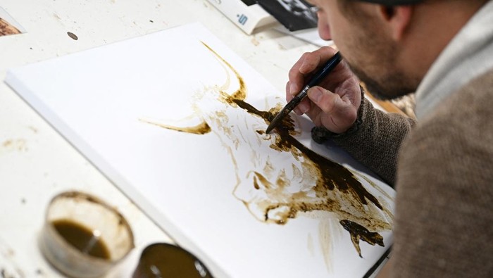 The Bavarian artist Werner Haertl paints with cow dung in his atelier in Reichersbeuern, Germany, December 4, 2024. REUTERS/Angelika Warmuth