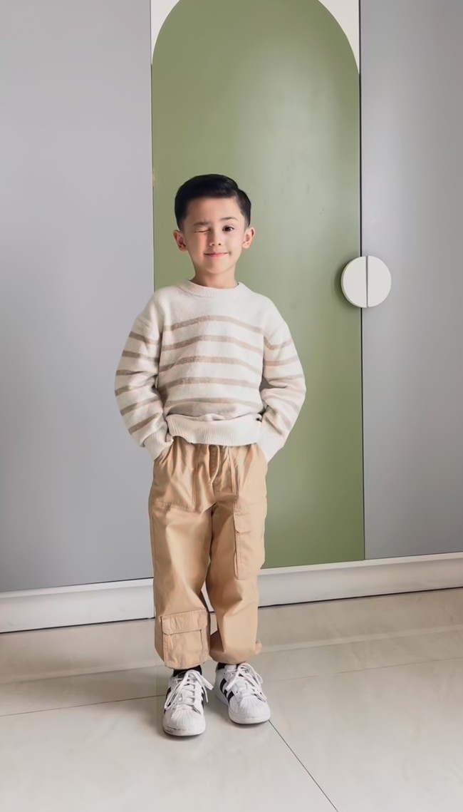 Dalam video yang dibagikan Saka tampak beberapa kali berganti busana. Untuk look kedua dirinya mengenakan sweater garis-garis berwarna coklat dipadukan dengan celana panjang senada. Foto: Instagram/@andhiiikapratama