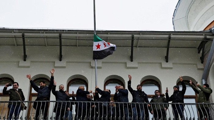 People who introduced themselves as members of the Syrian diaspora pose with the Syrian opposition flag outside the Embassy of Syria in Moscow, Russia December 9, 2024. REUTERS/Yulia Morozova