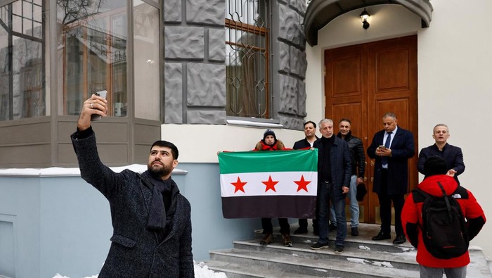 People who introduced themselves as members of the Syrian diaspora pose with the Syrian opposition flag outside the Embassy of Syria in Moscow, Russia December 9, 2024. REUTERS/Yulia Morozova
