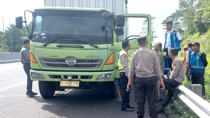 Evakuasi sopir truk menggantung di spion truk.