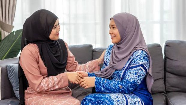 Two Malay Women With Baju Kurung and Hijab Greeting to Each Other.