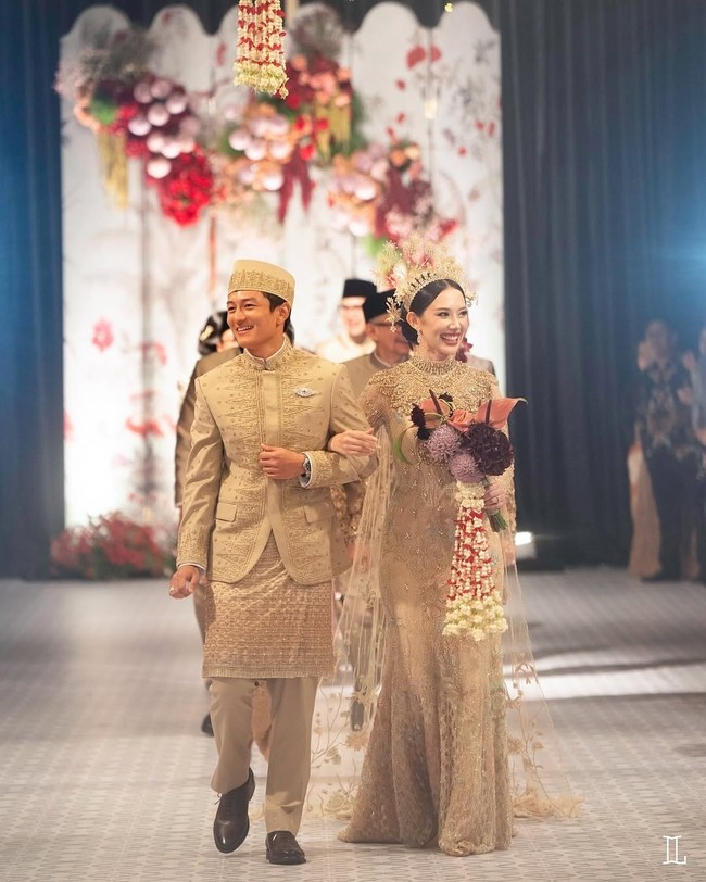 Rio Haryanto tak kalah tampil menawan. Pria 31 tahun ini mengenakan setelan beskap bernuansa emas. Aksen kain tentun dengan benang emas memperkuat sisi tradisional adat Betawi. Foto: Instagram/@leonardiwedding @itsfrankywu