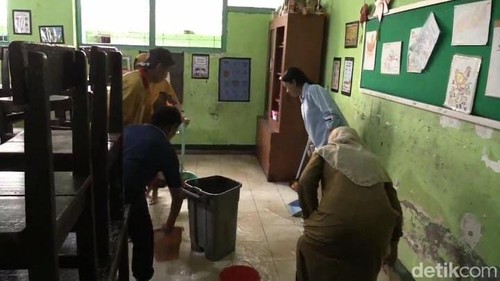 Sejumlah pegawai membersihkan genangan air di salah satu ruangan kelas di SD 3 Ampenan, Mataram, NTB, Selasa (10/12/2024). (Foto: Nathea Citra/detikBali)