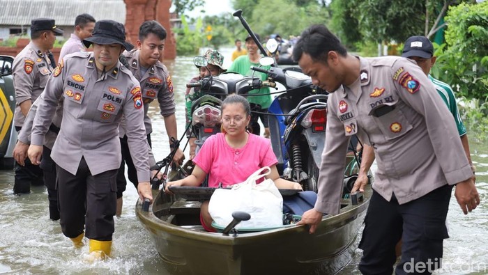 Anggota Polres Mojokerto membantu korban banjir.