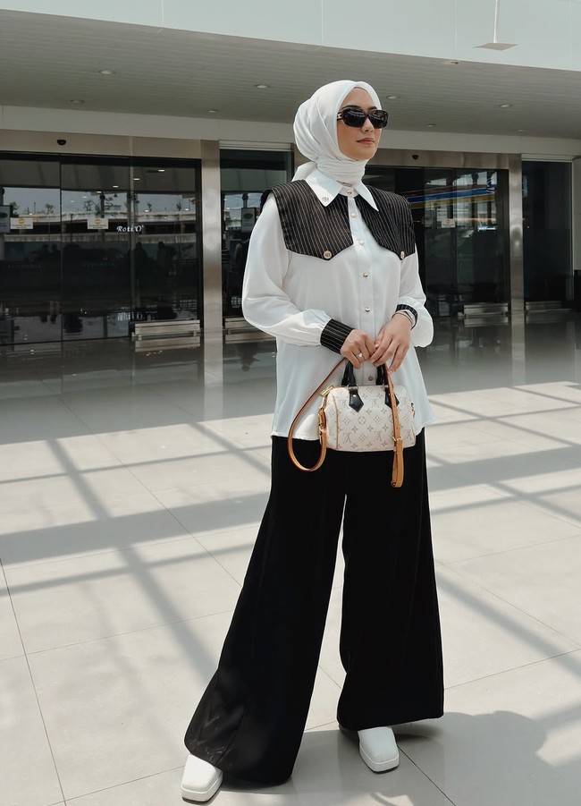 Ketika sedang di lokasi syuting, wanita yang akrab disapa Ciki ini tampil chic dengan kemeja putih aksen motif garis bagian bahu. Dipadukan dengan palazzo pants hitam. Foto: Dok. Instagram @citraciki.