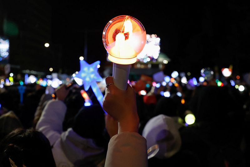 Ratusan penggemar K-pop di Korea Selatan ikut demo untuk mendesak pemakzulan Presiden Yoon Suk Yeol. Lightstick yang mereka bawa membuat suasana demo berwarna.