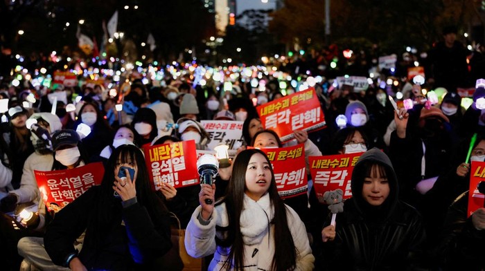 Ratusan penggemar K-pop di Korea Selatan ikut demo untuk mendesak pemakzulan Presiden Yoon Suk Yeol. Lightstick yang mereka bawa membuat suasana demo berwarna.
