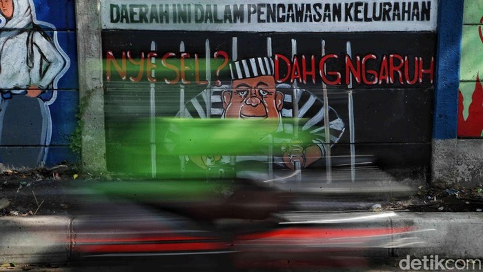 Sejumlah warga melintas di depan mural kawasan Warakas, Tanjung Priok, Jakarta Utara, Kamis (12/12/2024). Mural bertemakan pesan sosial itu memberikan pesan untuk menghindari narkoba, tawuran dan menjaga lingkungan.