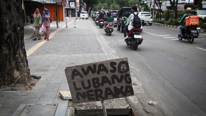 Trotoar di Jalan Ciater Raya, Tangerang Selatan (Tangsel) berlubang karena tidak ada penutup saluran air. Warga pun memasang papan bertuliskan 'lubang neraka'.